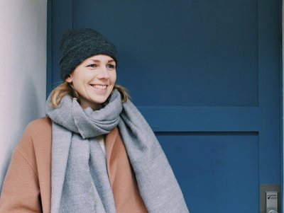 Karina steht vor einer blauen Tür und lächelt.