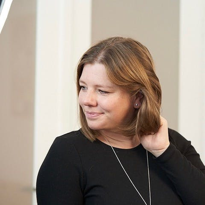 Ein Foto von Johanna, sie schaut nach rechts und greift sich mit der linken Hand ins schulterlange Haar.